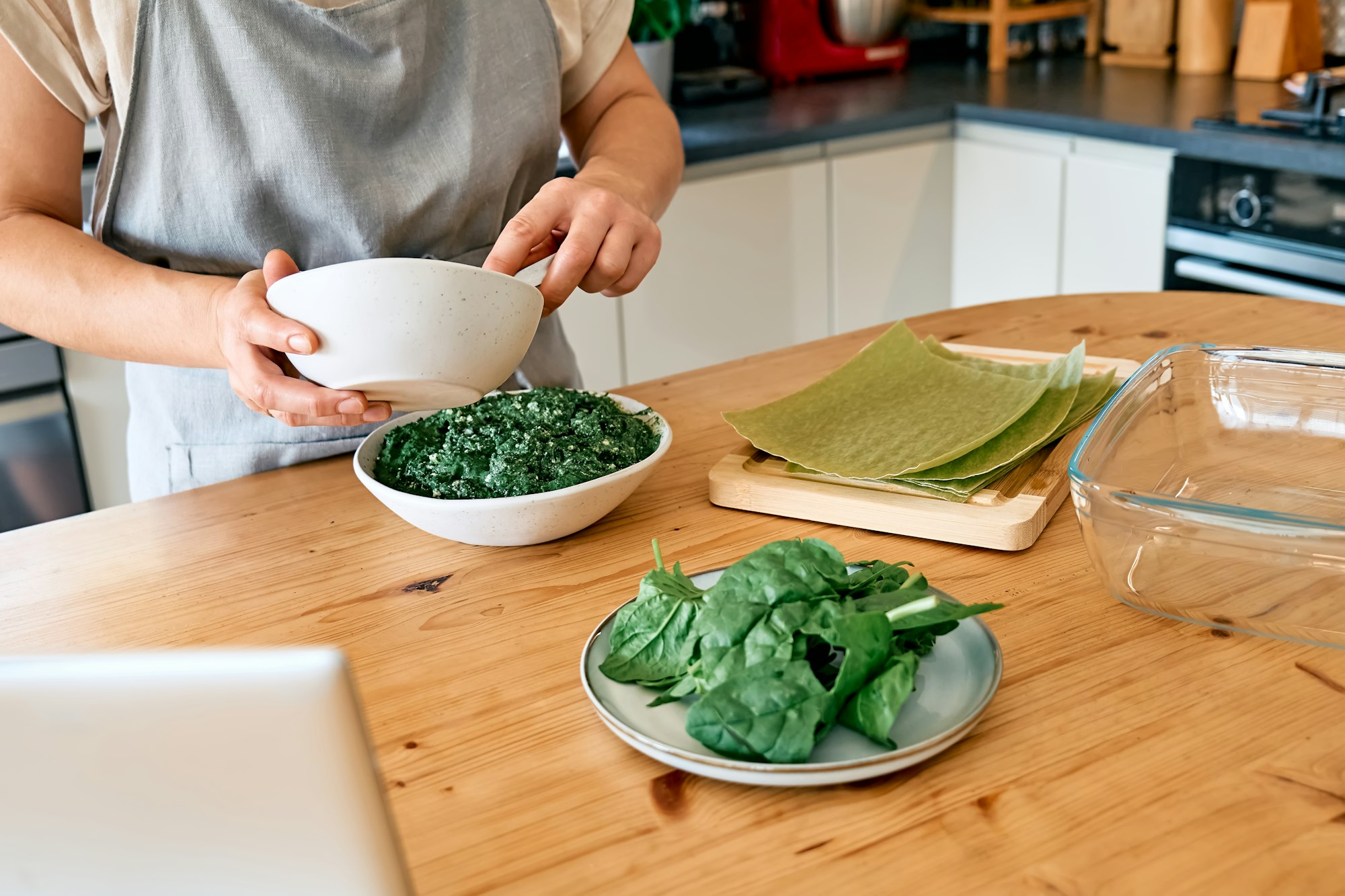 Hands of woman preparing homemade spinach and ricotta lasagna. Traditional Italian dish.