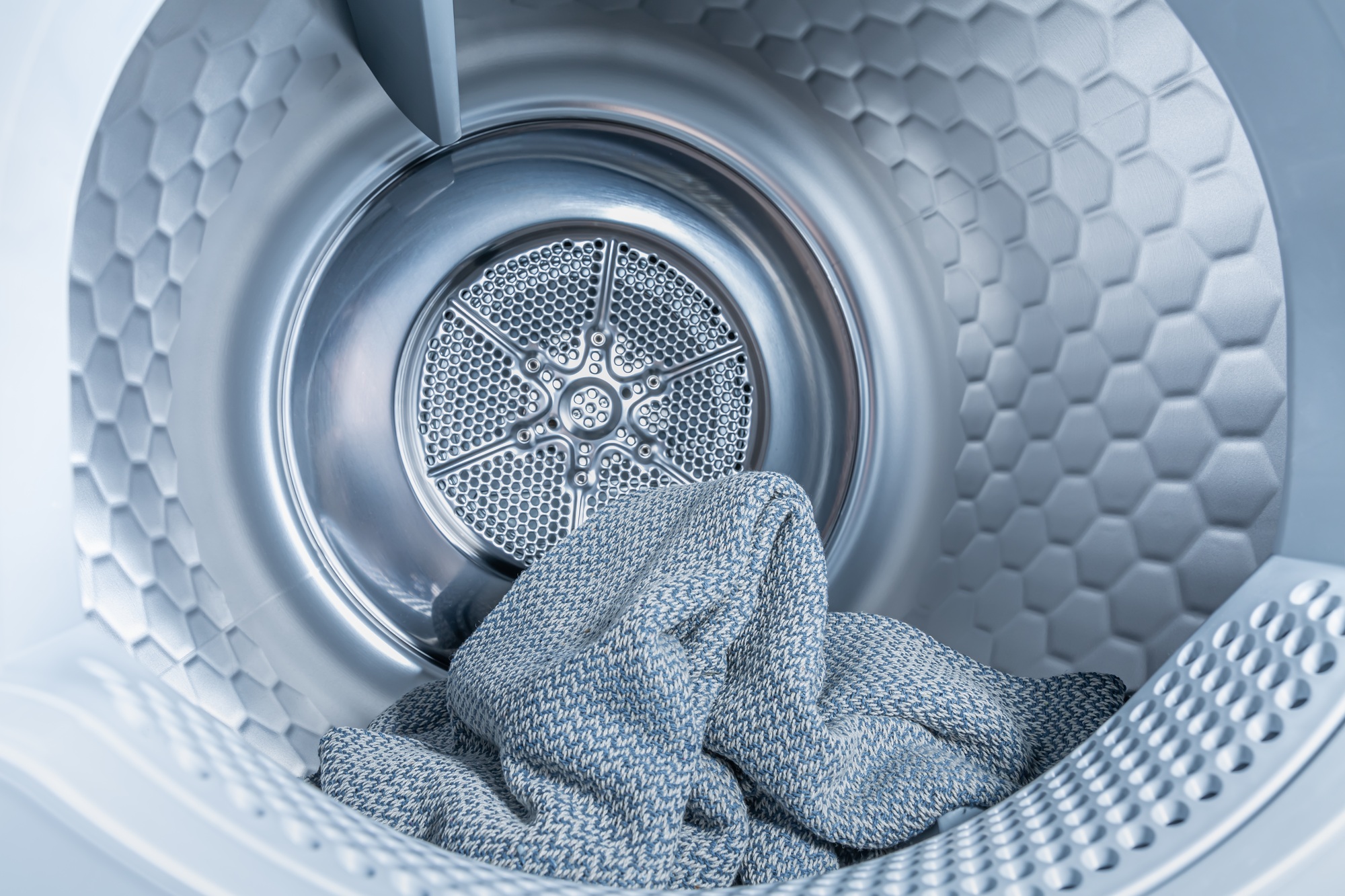 Inside of tumble dryer with clean laundry - new generation of heat pump dryer, household concept